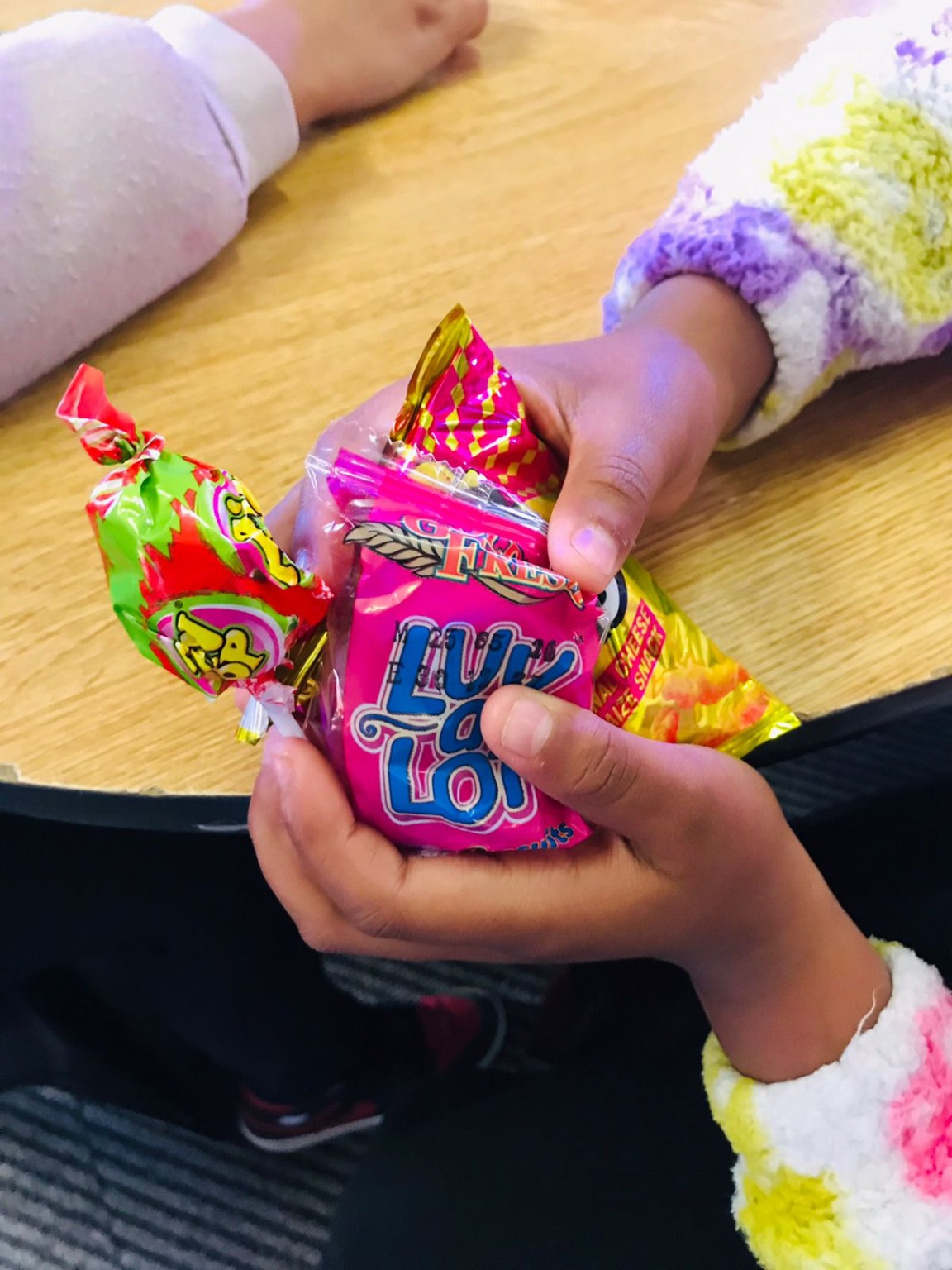 A child holding sweets shared during a YouthTable S.A. community activity